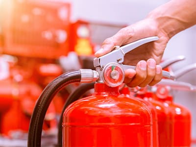 Top of a red fire extinguisher with hand on handle